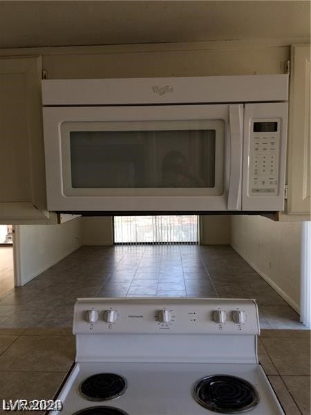 kitchen featuring white cabinets, tile counters, tile floors, and range