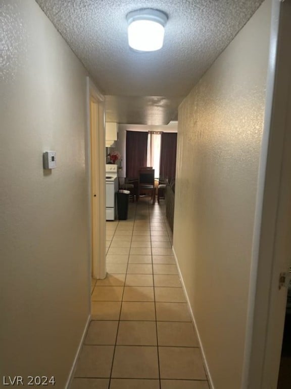 corridor with a textured ceiling and light tile floors