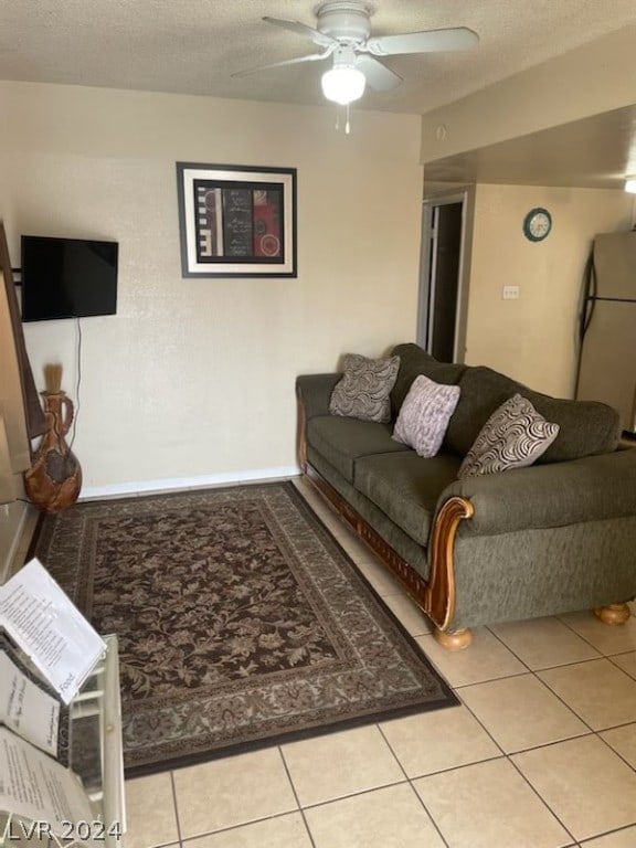 living room with tile floors, ceiling fan, and a textured ceiling