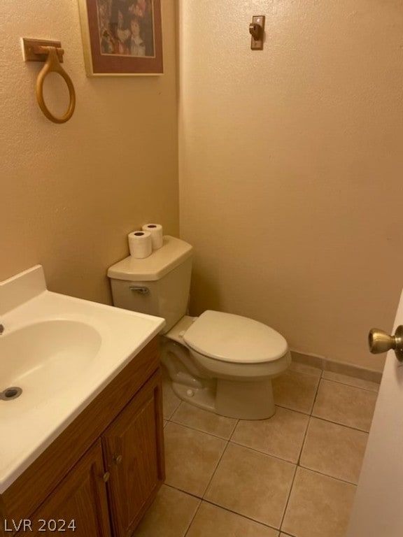 bathroom featuring tile flooring, vanity, and toilet