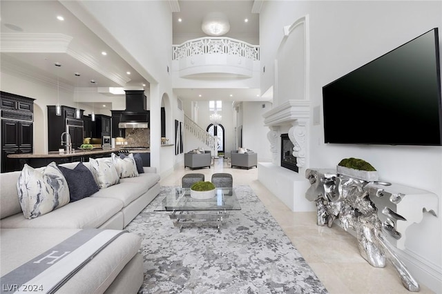 living room featuring ornamental molding, a towering ceiling, sink, and light tile patterned floors