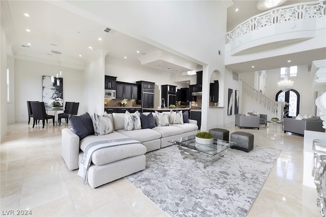 living room featuring a high ceiling, ornamental molding, and a notable chandelier