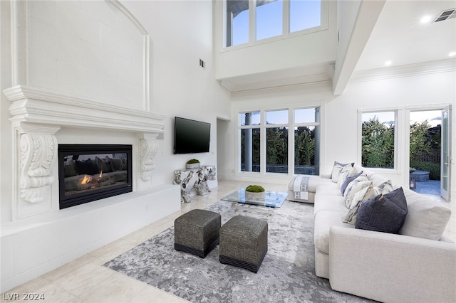 living room featuring a high ceiling, ornamental molding, a healthy amount of sunlight, and a fireplace