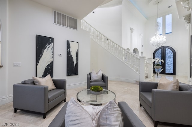 living room with a notable chandelier, a towering ceiling, and french doors