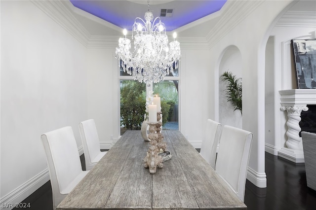 dining area with crown molding, wood-type flooring, a chandelier, and a raised ceiling