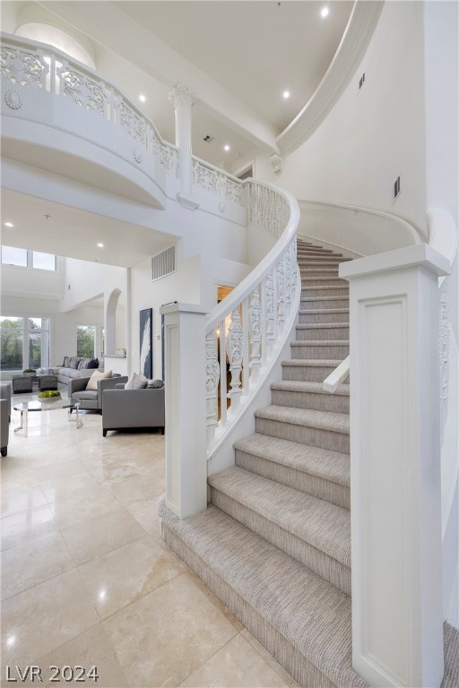 stairway with tile patterned flooring and a towering ceiling