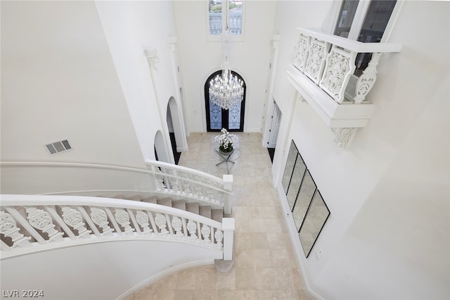 staircase with a high ceiling and an inviting chandelier