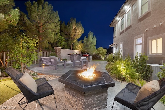 patio at night with central AC unit and an outdoor living space with a fire pit