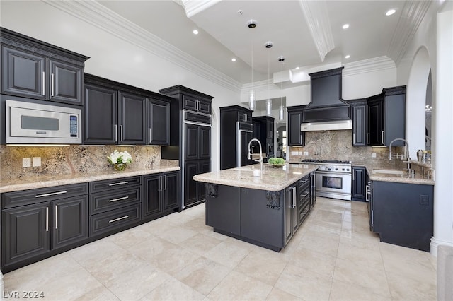 kitchen with pendant lighting, sink, stainless steel appliances, custom range hood, and a center island with sink