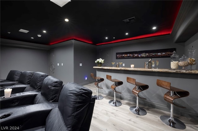 cinema with indoor bar, a raised ceiling, and light hardwood / wood-style flooring