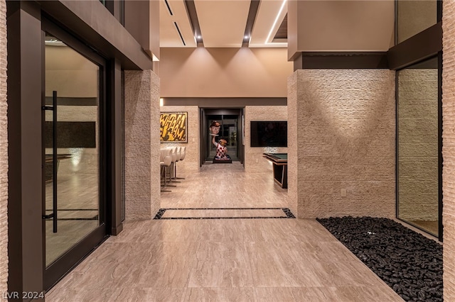 hallway with tile floors and a high ceiling