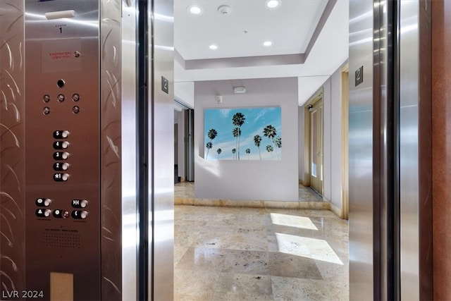 hallway with a raised ceiling and tile flooring