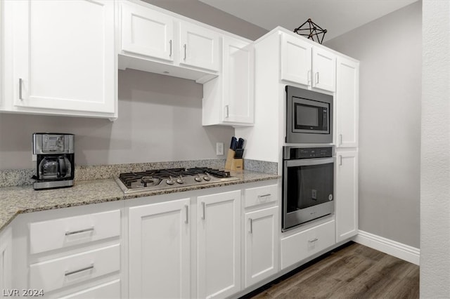 kitchen with appliances with stainless steel finishes, dark hardwood / wood-style flooring, white cabinets, and light stone countertops