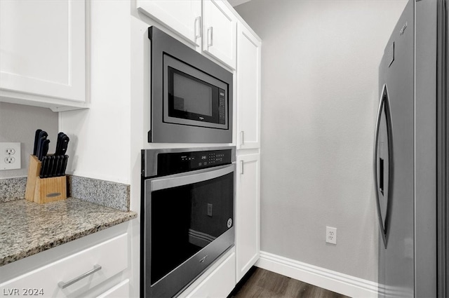 kitchen featuring appliances with stainless steel finishes, dark hardwood / wood-style flooring, white cabinetry, and light stone counters