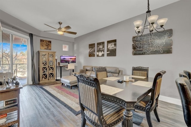 dining space featuring ceiling fan with notable chandelier and hardwood / wood-style flooring