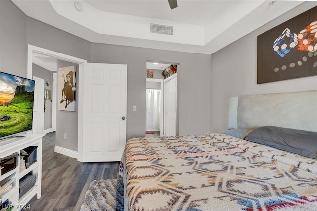 bedroom featuring dark hardwood / wood-style floors, a raised ceiling, and ceiling fan