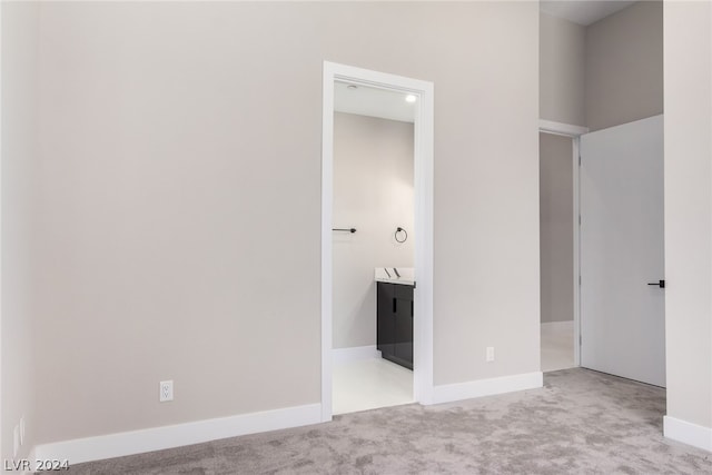 unfurnished bedroom featuring light colored carpet and ensuite bath