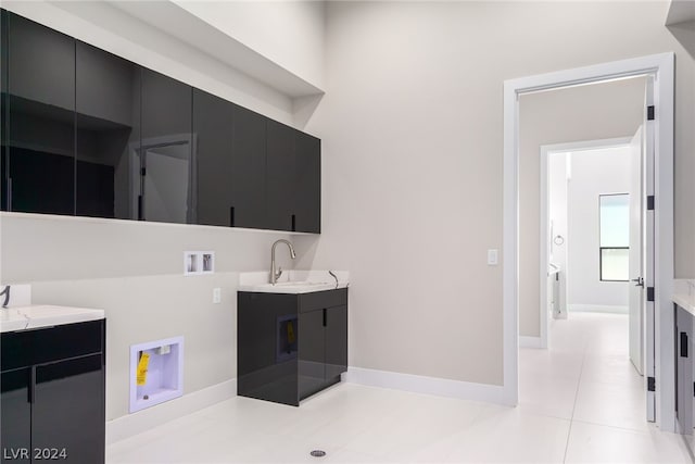 clothes washing area featuring sink, hookup for a washing machine, cabinets, and light tile patterned flooring