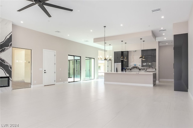 living room with ceiling fan with notable chandelier, a high ceiling, and light tile patterned flooring