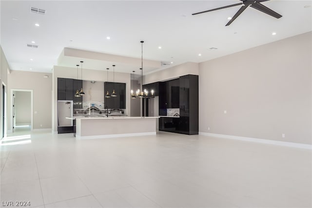 kitchen featuring ceiling fan with notable chandelier, decorative backsplash, hanging light fixtures, a large island, and light tile patterned flooring