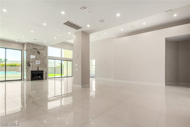 unfurnished room featuring a high ceiling, a fireplace, and light tile floors