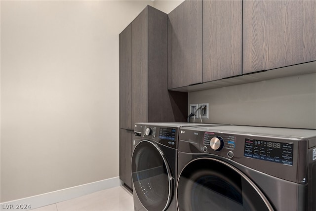 laundry area featuring cabinets, washer hookup, light tile floors, and washing machine and dryer