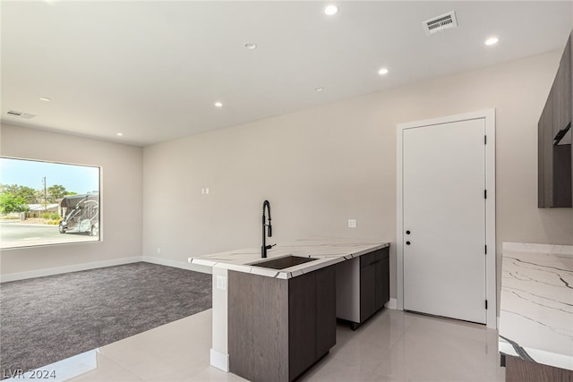 kitchen with dark brown cabinetry, sink, and light tile floors