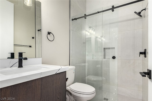 bathroom featuring a shower with shower door, toilet, and vanity with extensive cabinet space