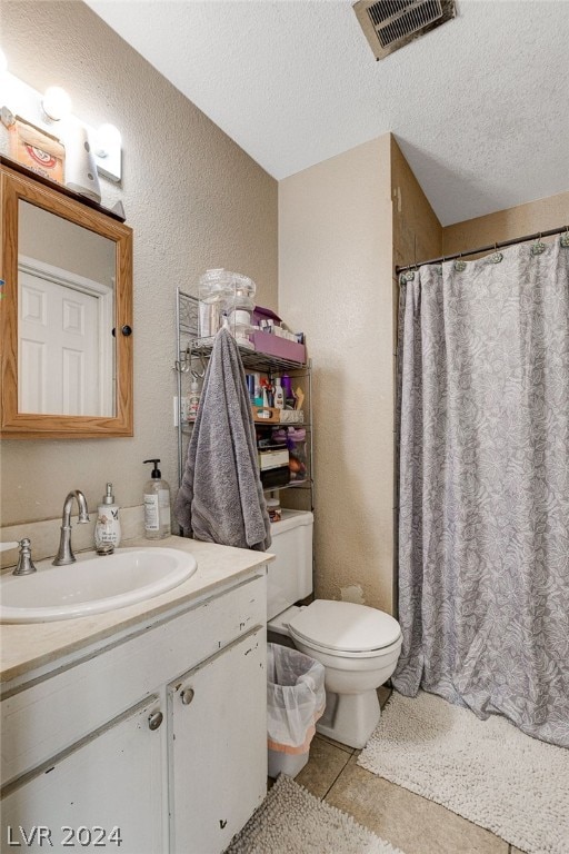 bathroom with a textured ceiling, vanity, tile floors, and toilet