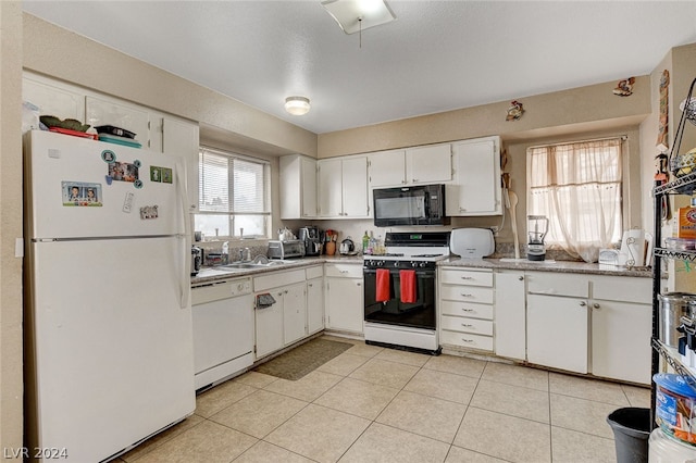 kitchen with white appliances, light tile floors, and white cabinetry