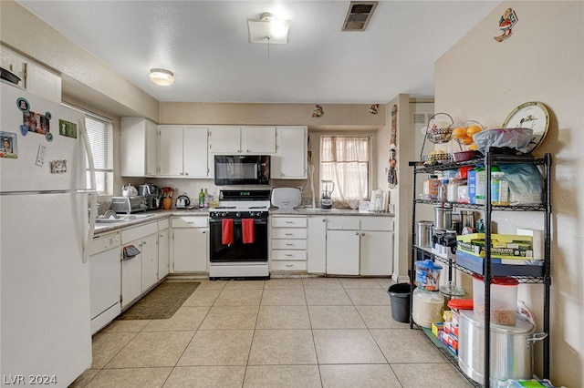 kitchen with white cabinets, a wealth of natural light, white appliances, and light tile flooring