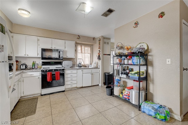 kitchen with white range, light tile flooring, and white cabinetry