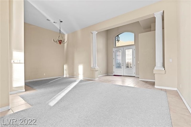 carpeted foyer featuring vaulted ceiling, french doors, and ornate columns