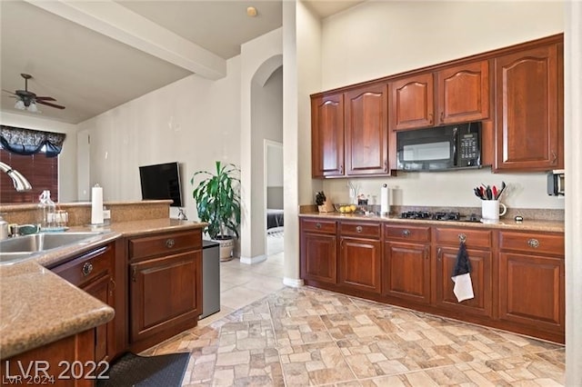 kitchen featuring beam ceiling, stainless steel gas stovetop, light tile floors, sink, and ceiling fan