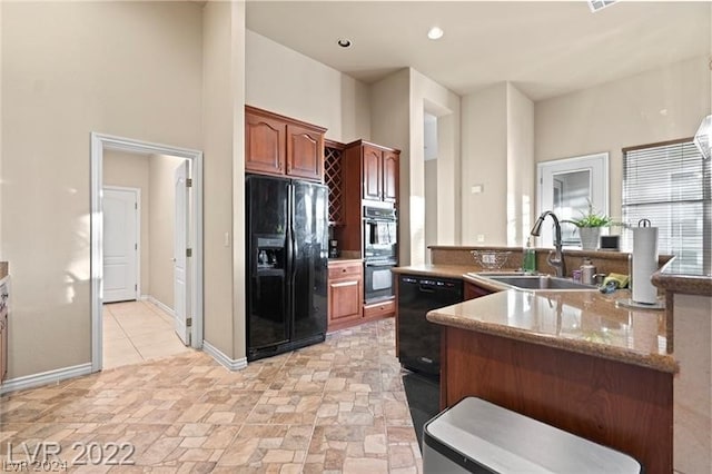 kitchen with light stone countertops, kitchen peninsula, light tile flooring, black appliances, and sink