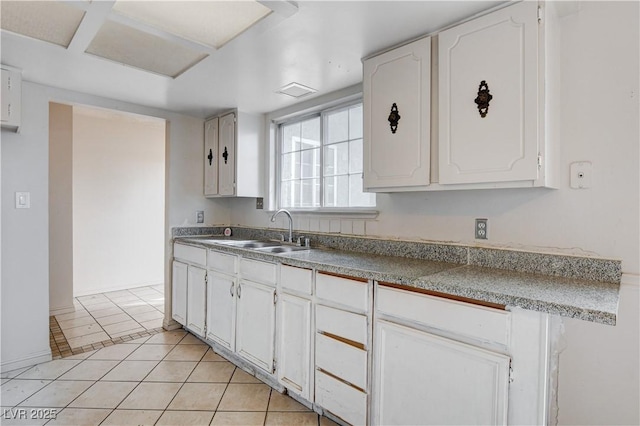 kitchen with a sink, white cabinets, and light tile patterned flooring