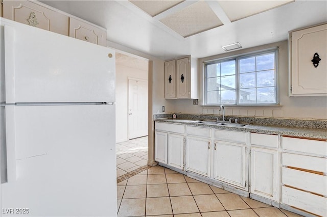 kitchen featuring a sink, light tile patterned floors, white cabinets, and freestanding refrigerator