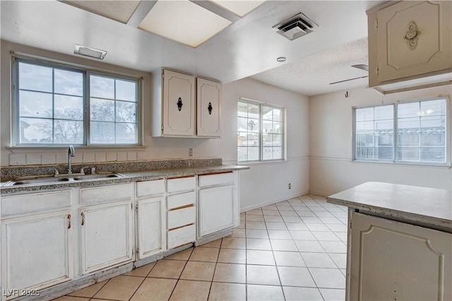 kitchen featuring light tile patterned floors, a ceiling fan, visible vents, a sink, and a textured ceiling