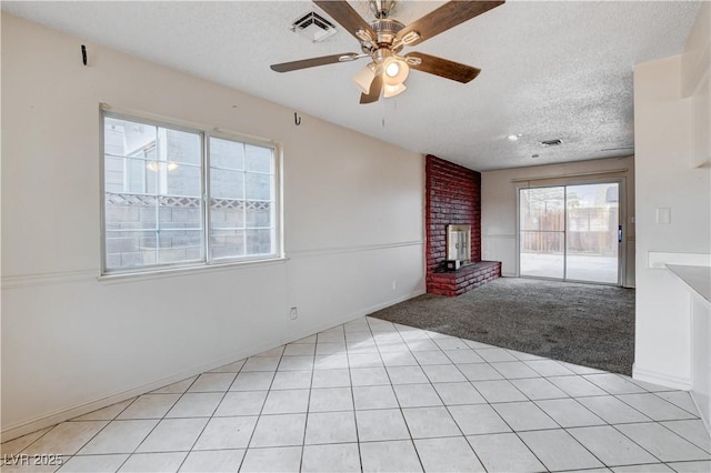 unfurnished living room with visible vents, light carpet, a textured ceiling, a brick fireplace, and ceiling fan