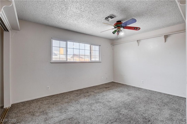 carpeted spare room featuring visible vents, a textured ceiling, and ceiling fan