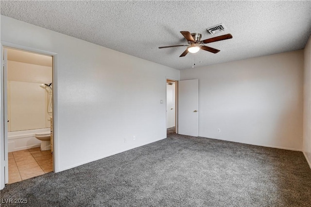 unfurnished bedroom with visible vents, ceiling fan, carpet floors, a textured ceiling, and ensuite bath