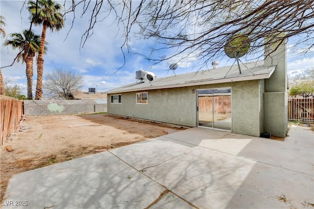 rear view of house featuring a patio area, stucco siding, and a fenced backyard