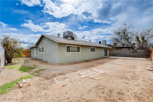 back of house featuring stucco siding, central air condition unit, and a fenced backyard