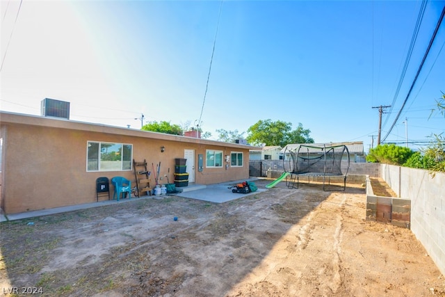 back of property with a trampoline and a patio