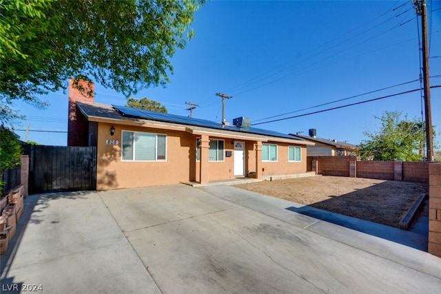 ranch-style house featuring solar panels and a patio area