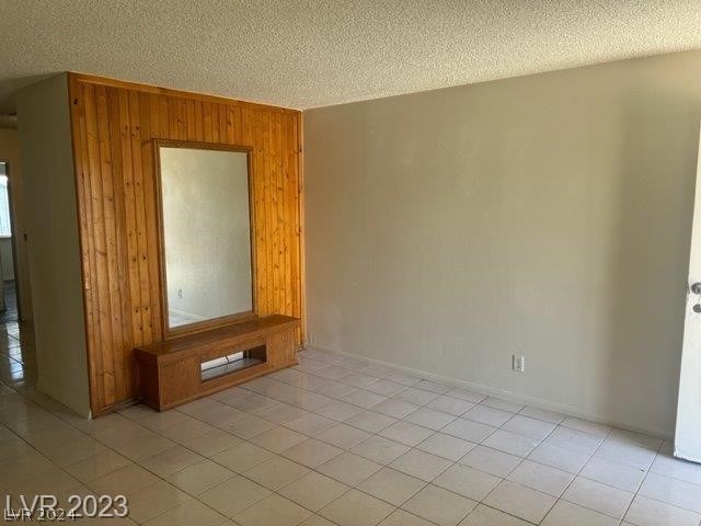 tiled spare room with wooden walls and a textured ceiling