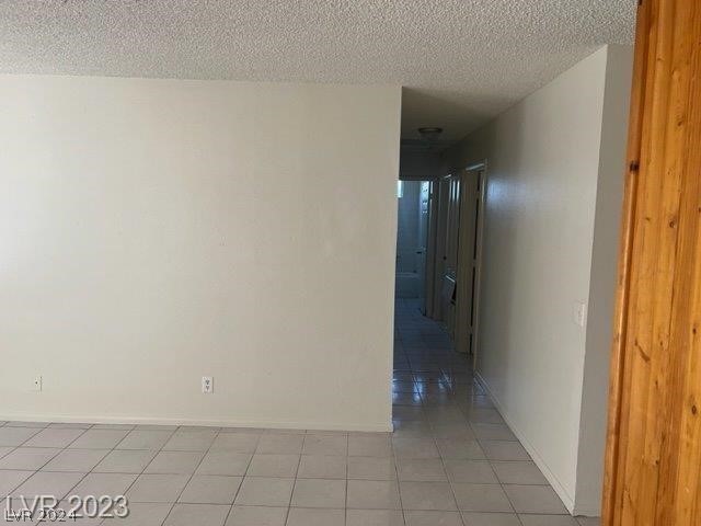 hall with a textured ceiling and light tile flooring