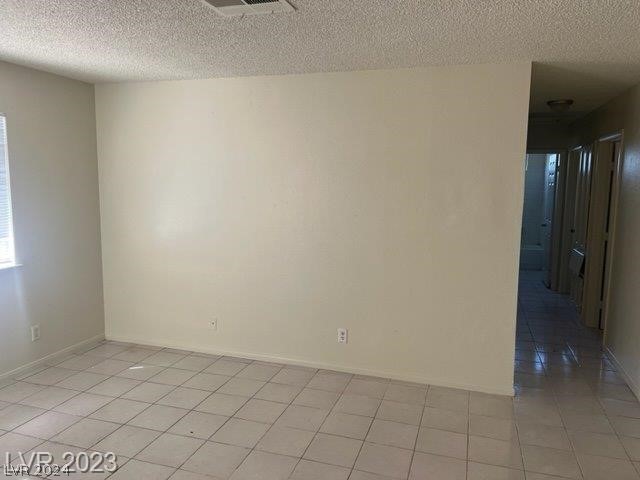 spare room with a textured ceiling and light tile flooring