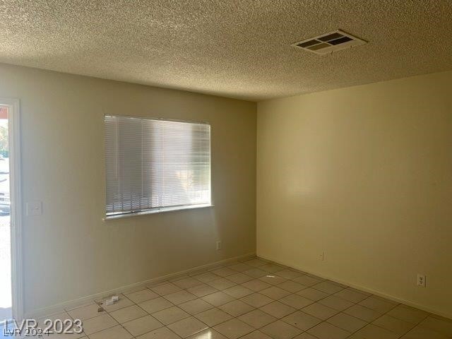 tiled spare room featuring a textured ceiling