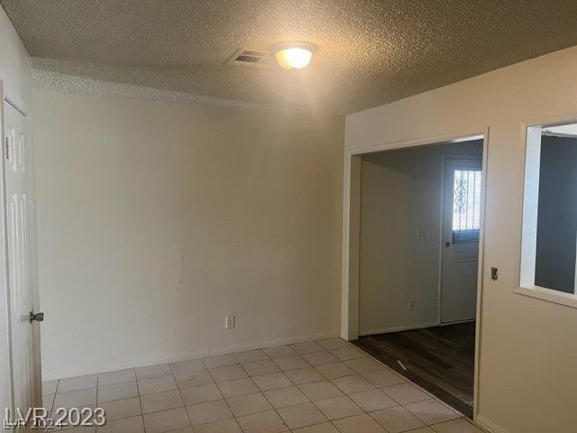 tiled empty room featuring a textured ceiling